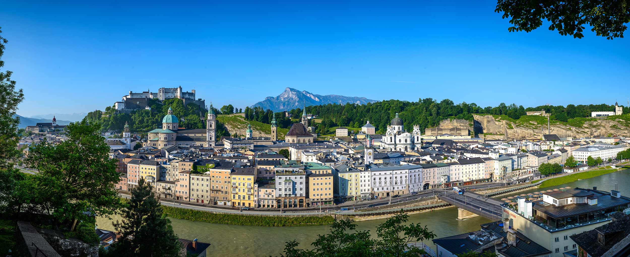 Panoramic view of Salzburg with Hohensalzburg Fortress and historic Old Town under blue summer sky