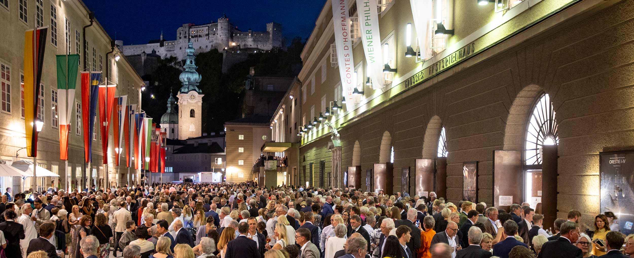 Crowds in front of Salzburg Festival Hall during summer evening with Hohensalzburg Fortress in background – Salzburg No. 1 Lonely Planet