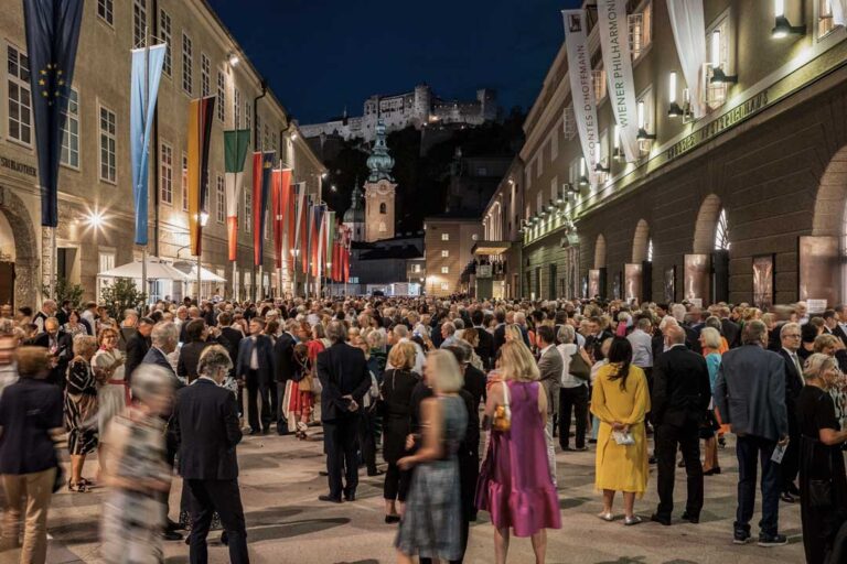 Salzburg Festival audience in the Hofstallgasse with Hohensalzburg Fortress at night
